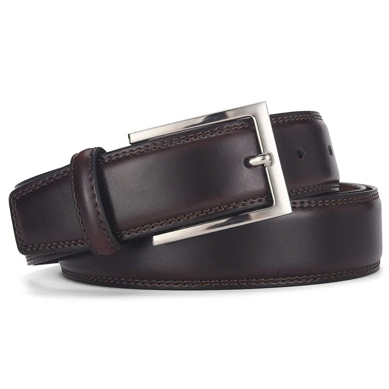 Men's classic black genuine leather belt with a silver-toned alloy pin buckle on a flat surface.