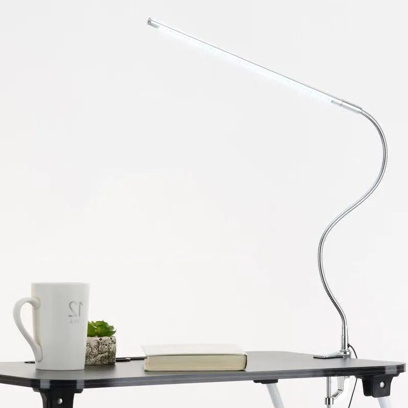 Silver long arm LED clip table lamp with USB cable, shown illuminating a nail art workspace.
