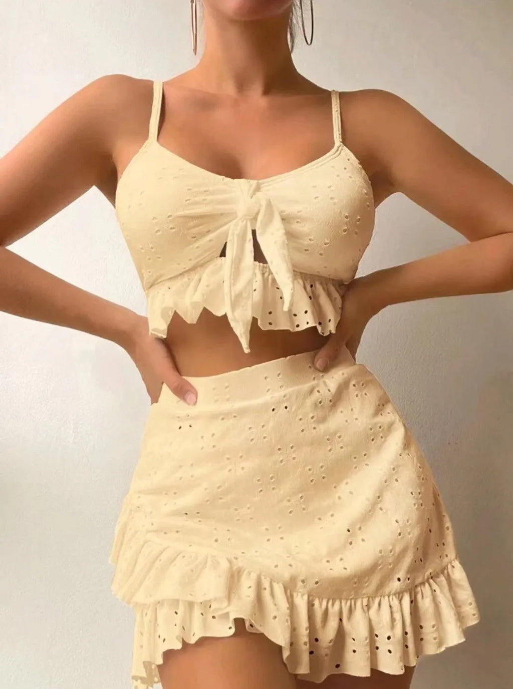 Women's white three-piece bikini swimsuit with a split hip skirt laid flat.