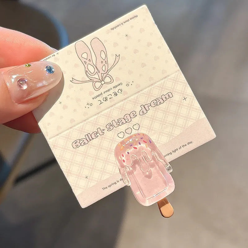 Close-up of a resin hair clip with a colourful cartoon ice cream design, shown in beige.