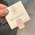 Close-up of a resin hair clip with a colourful cartoon ice cream design, shown in beige.