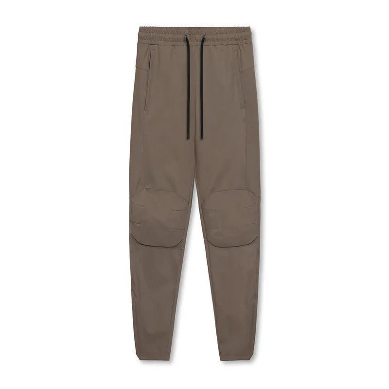 Man wearing dark grey loose-fit ankle-tied running pants made from quick-drying polyester fabric.