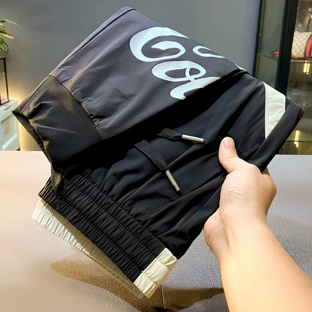 Men's solid black ultra-thin ice silk ankle-banded cropped casual trousers laid flat.