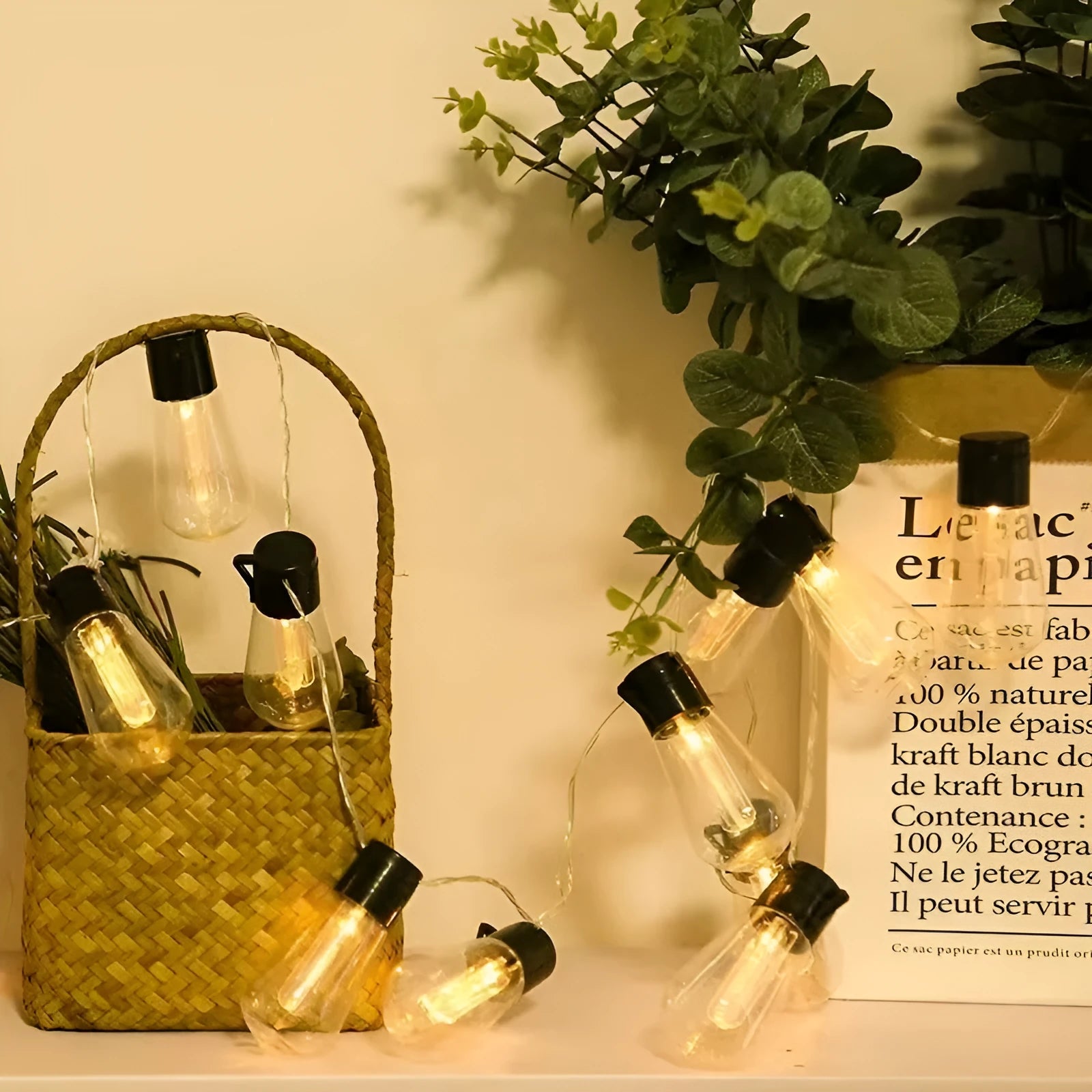 Retro infusion bottle shaped glass bulb outdoor fairy lights with green cable, shown in garden setting.