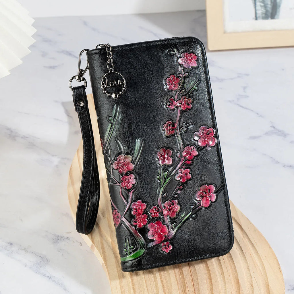 Black embossed floral handbag with hand-painted details and a zipper closure.