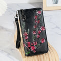 Black embossed floral handbag with hand-painted details and a zipper closure.