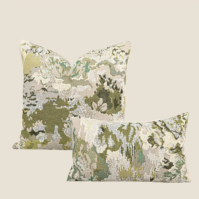 Green square pillow with abstract botanical plant and flower pattern on a sofa.