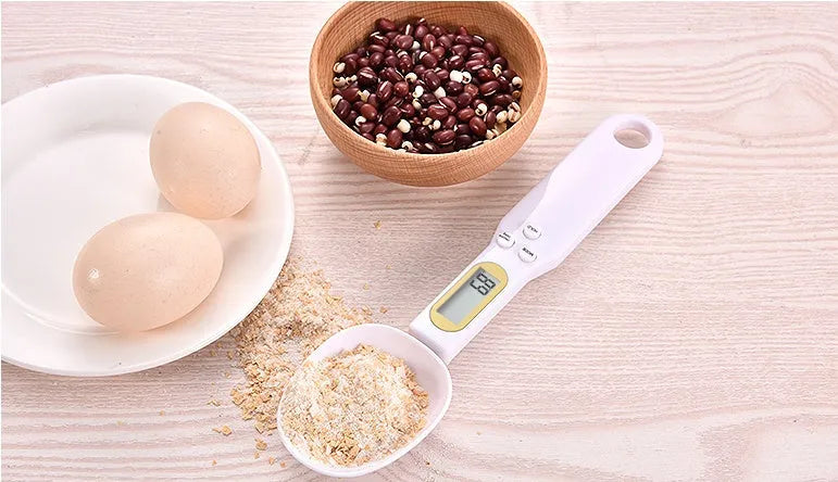 Black electronic measuring spoon scale showing digital display, placed on a kitchen counter.