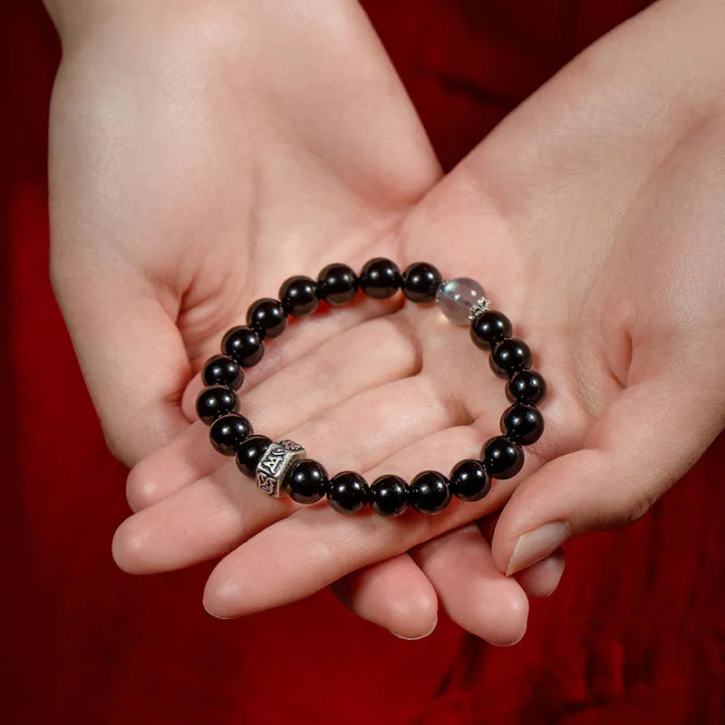 Close-up of an 8mm obsidian beaded bracelet with zodiac and Buddhist bodhisattva designs.