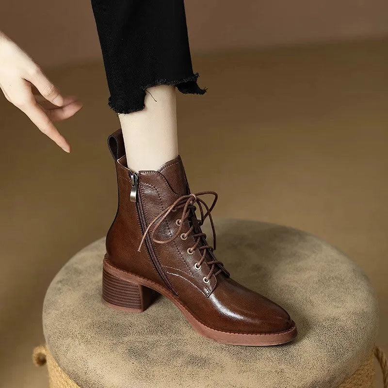 Women's black pointed-toe ankle boots with a short tube and block heel on a plain background
