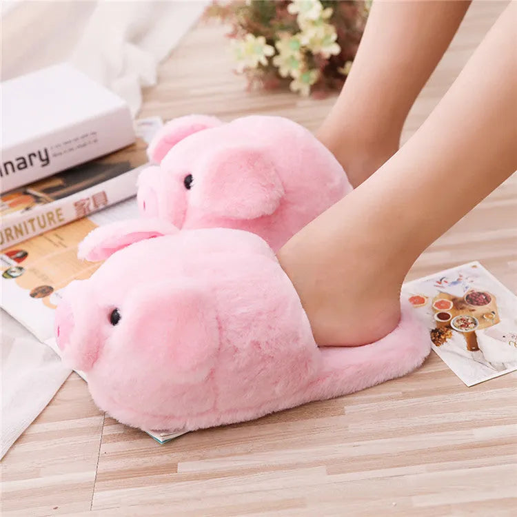 Pink pig-shaped plush floor slippers for adults on a white background.