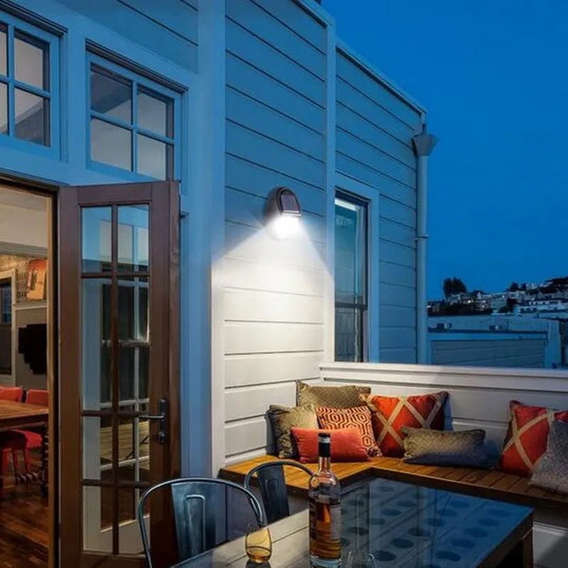 Compact black rectangular solar-powered LED wall light mounted on an outdoor wall.