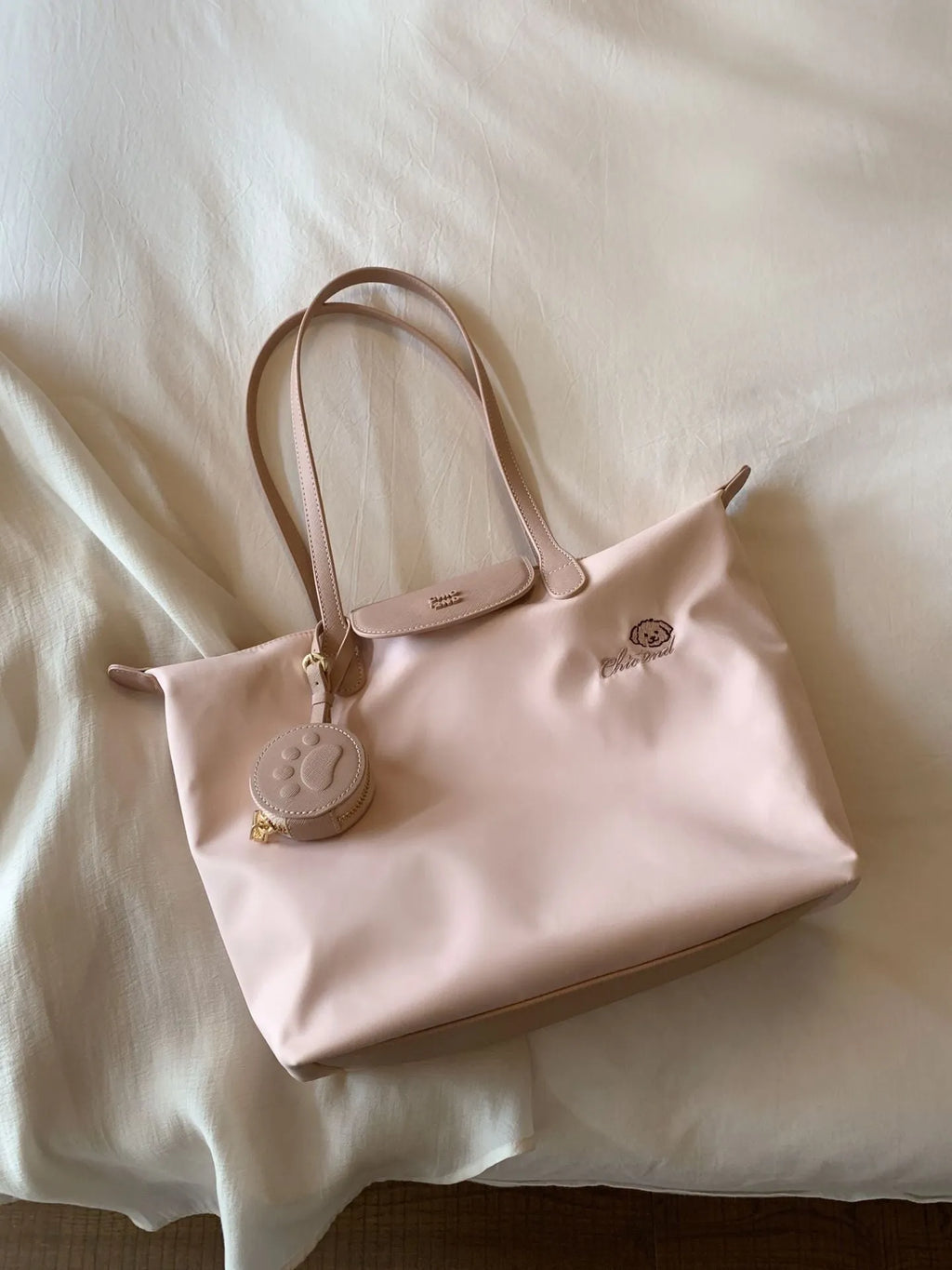 Women's large beige tote shoulder bag with external pockets and a horizontal square shape.