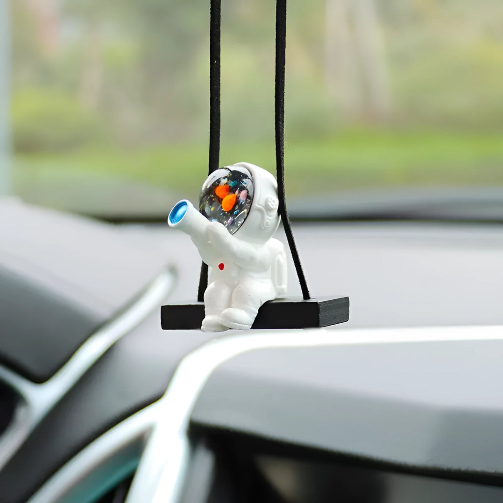 Colourful resin astronaut cartoon character car pendant hanging from a sun visor.