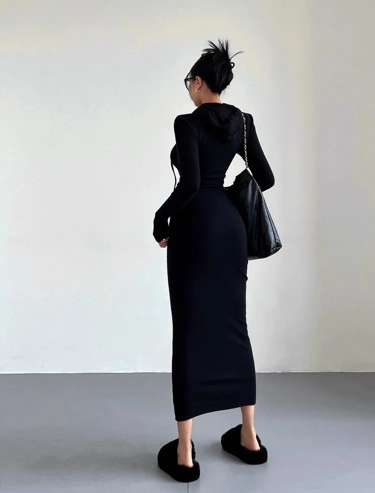 A woman wearing a grey hooded sheath dress with long sleeves and an over-the-knee length.