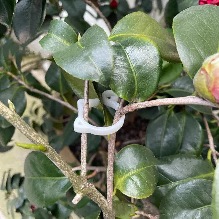 Small red cat-shaped plastic plant clip on a green leaf stem