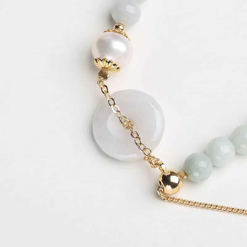 Green jade peace buckle charm and pearl beaded bracelet for women on a white background.