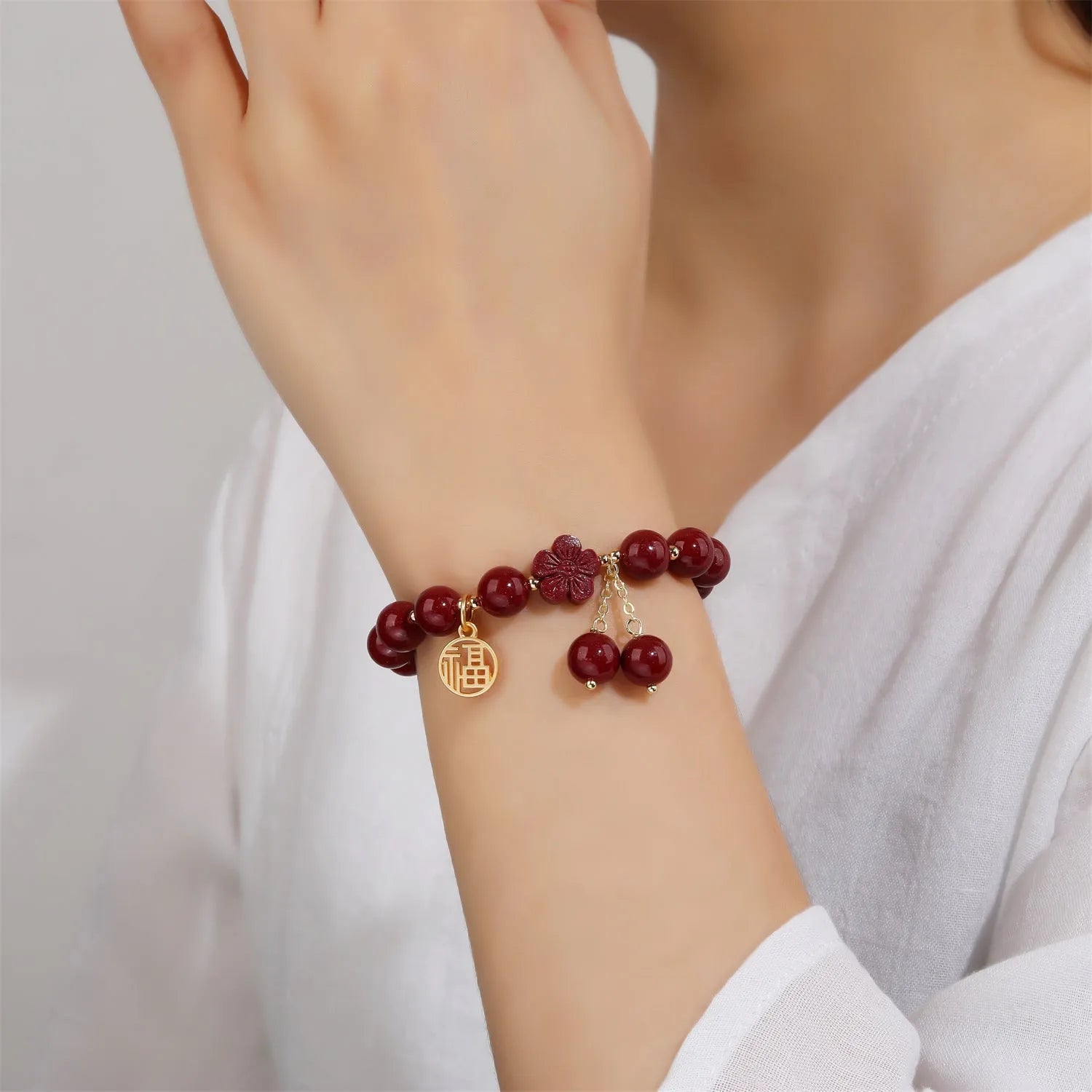 Close-up of a purple gold sand cinnabar bracelet with a fu character charm and adjustable tassel.