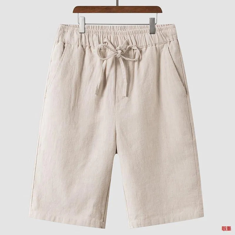 A pair of men's beige linen shorts with a loose, cropped cut and a mid-rise elasticated waistband.