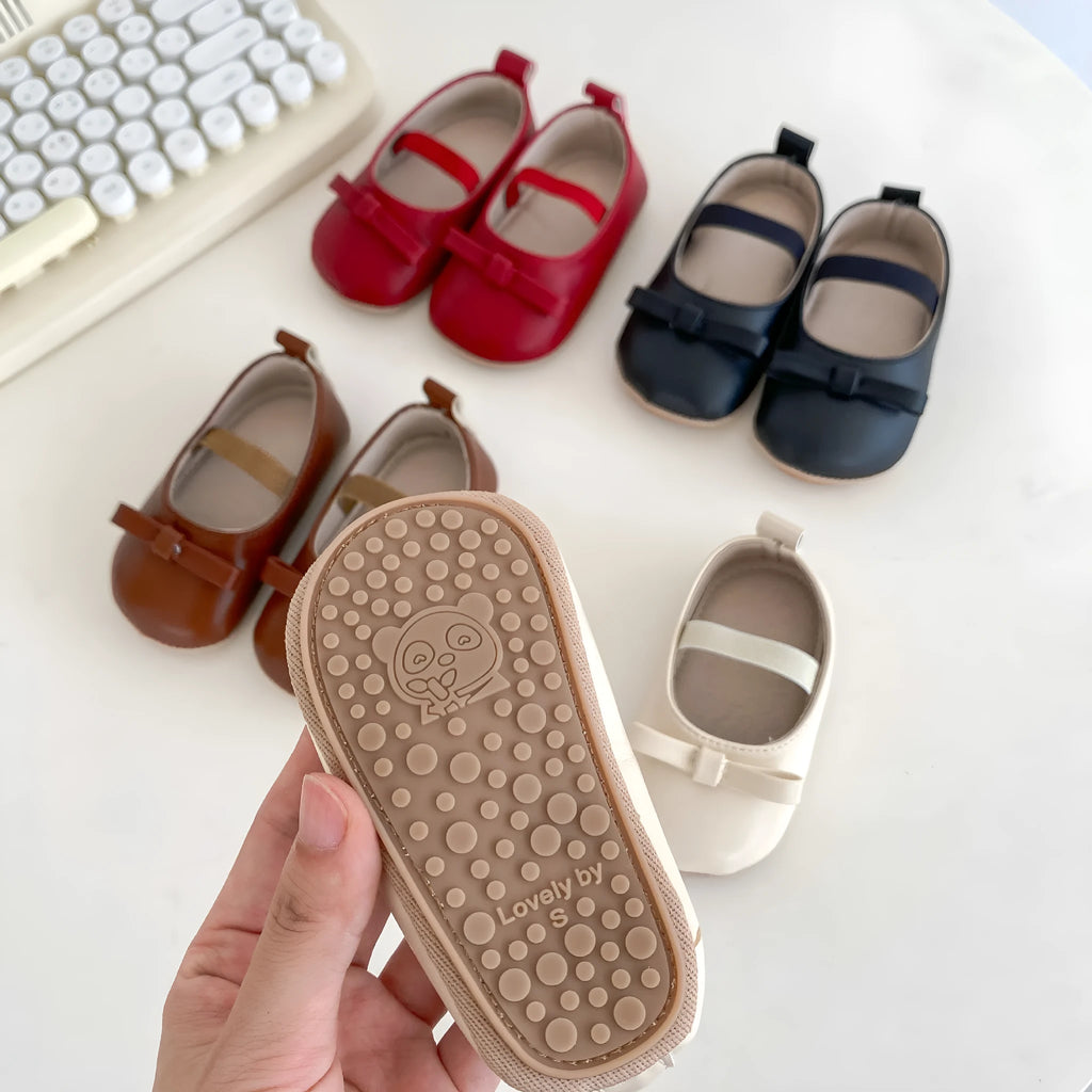 Baby shoes in white with bow detail, non-slip rubber sole, and elastic band fastening