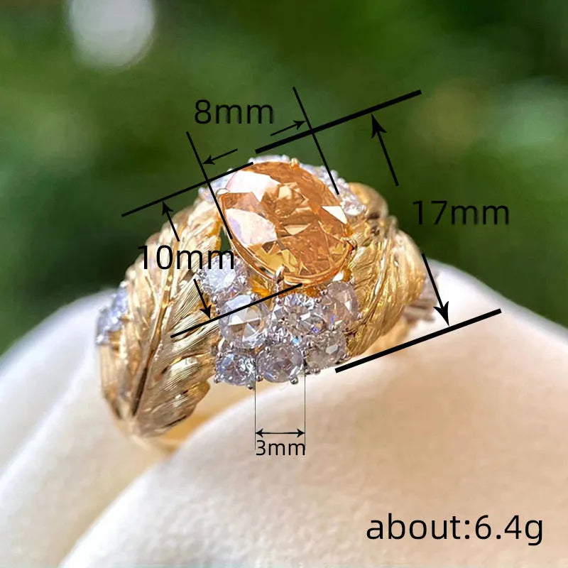 Gold-colour women's ring with a detailed embossed feather design and a central yellow zircon stone on a geometric copper band.