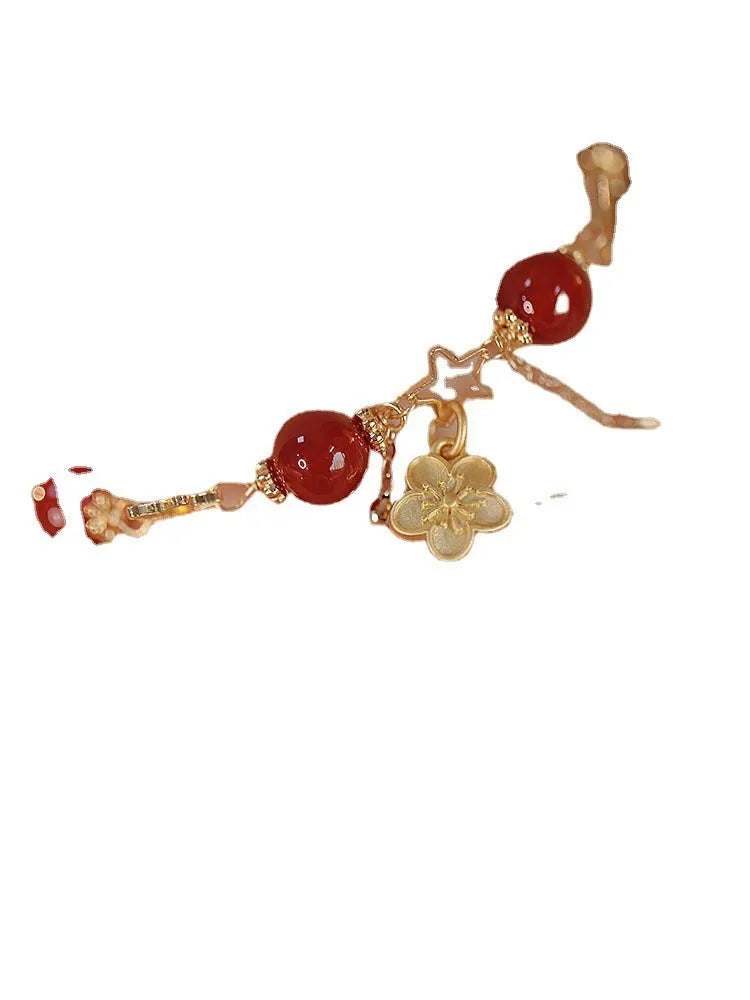 Close-up of a red agate double layer bracelet with floral and peach blossom detailing on a woman's wrist.