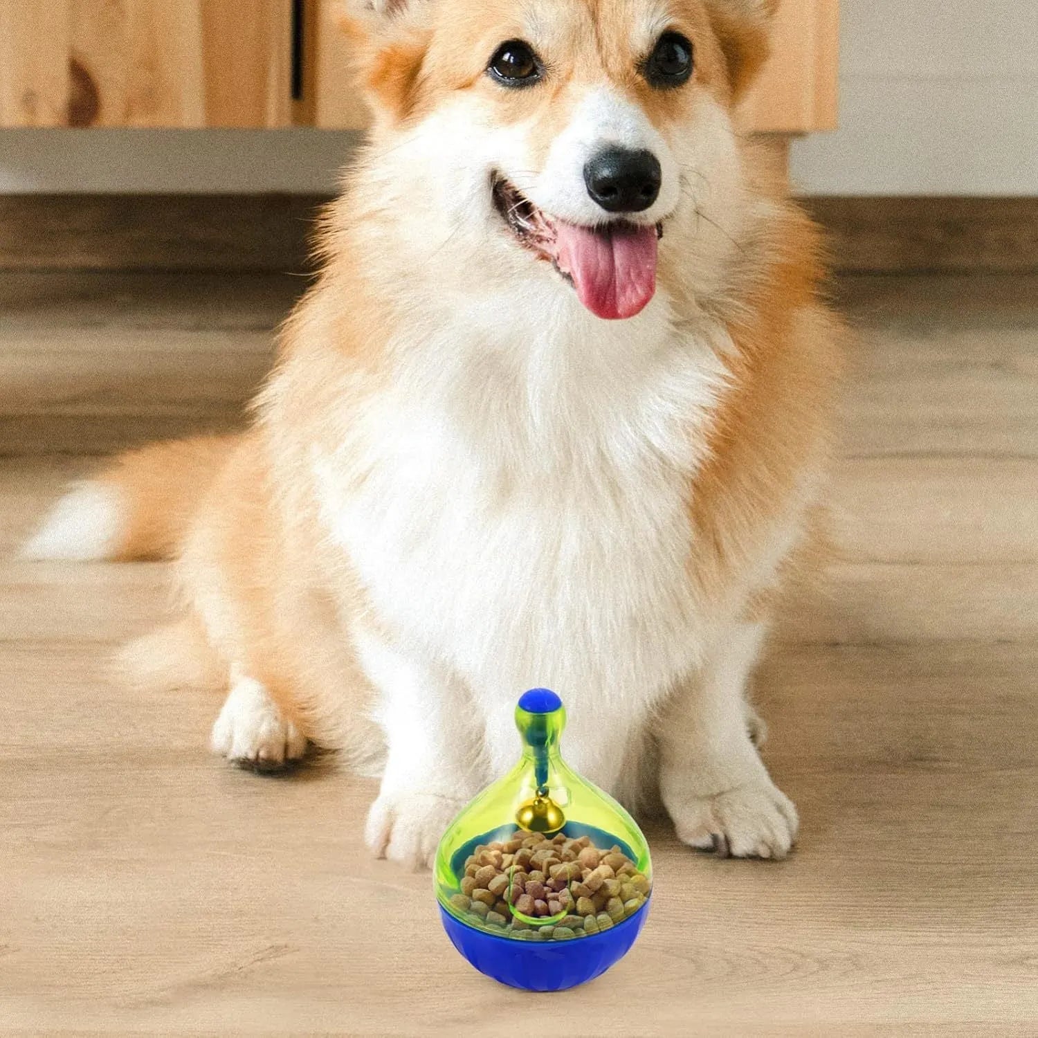 White tumbler-shaped dog and cat treat dispenser toy on a wooden floor