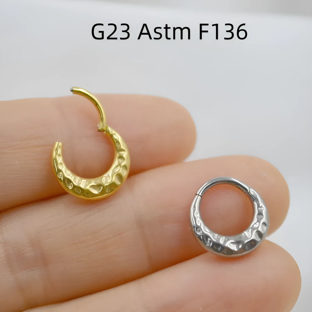 Close-up of a titanium alloy concave-convex nose ring in gold finish, showing detailed carving texture.