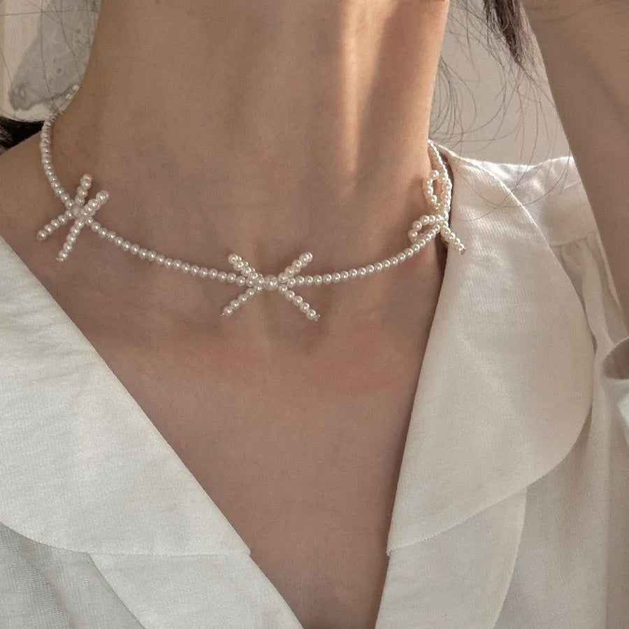 Women's white bow-shaped imitation pearl necklace with an adjustable chain.