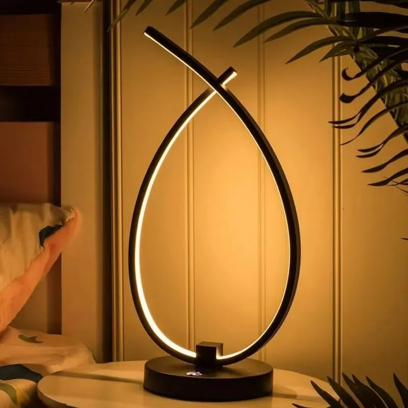 Black water drop shaped USB desk lamp with touch control on a wooden table