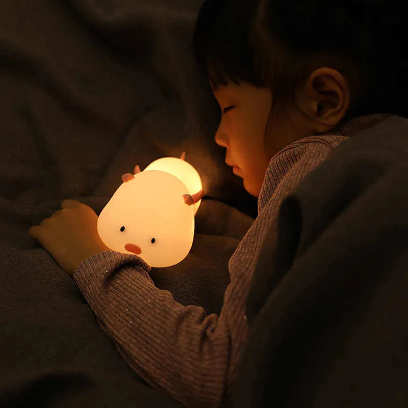 Cute pig silicone night light in Pink with sleeping face design on a wooden table