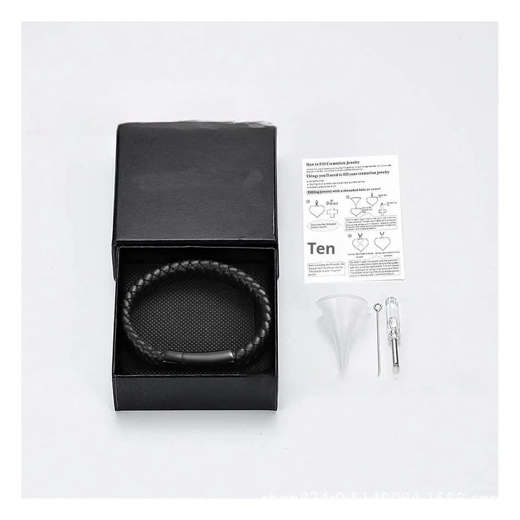 Black leather and stainless steel casket bracelet with engraved text on a gift box.