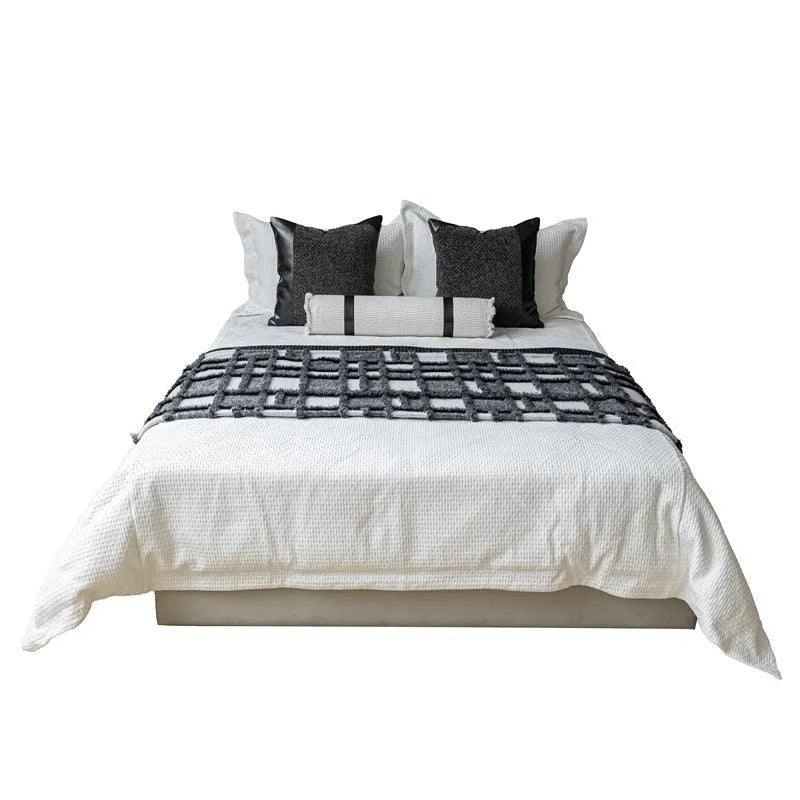 Grey and white plaid bed runner blanket with matching pillow on a 1.5m bed in a minimalist bedroom setting.