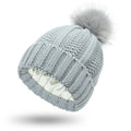 Women's black knit beanie with a faux fur pom pom and a visible satin lining inside the crown.