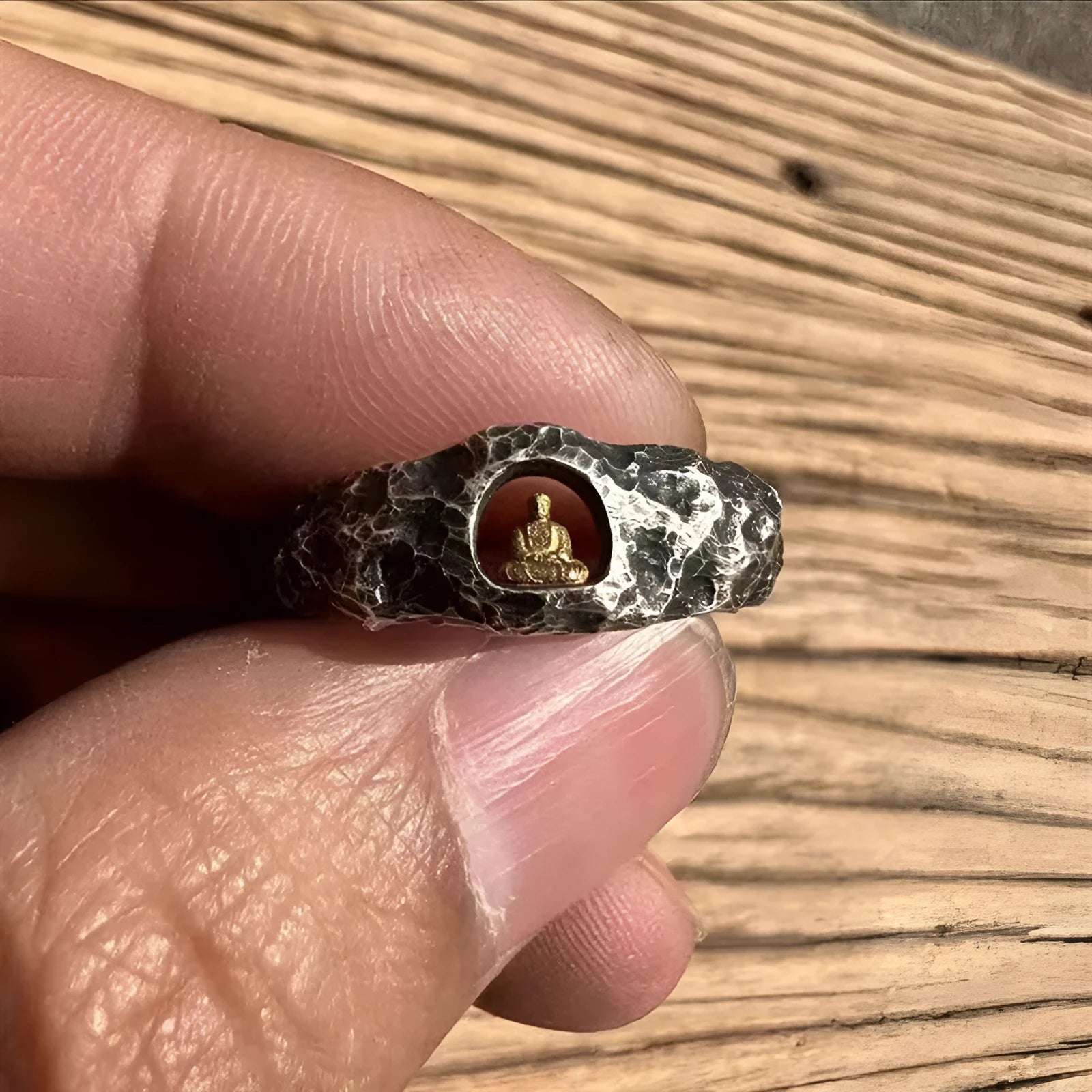 Close-up of a hand-forged copper Grotto Buddha Ring with rock texture, showing the Buddha motif on a size 8 band.