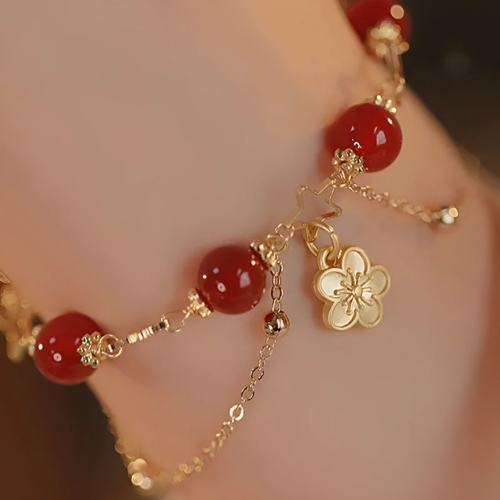 Close-up of a red agate double layer bracelet with floral and peach blossom detailing on a woman's wrist.