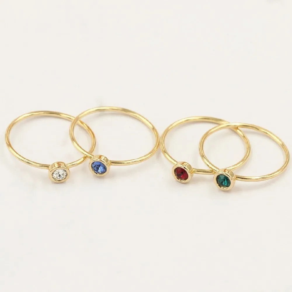 Gilded copper knuckle ring with a blue cubic zirconia stone on a model's hand.