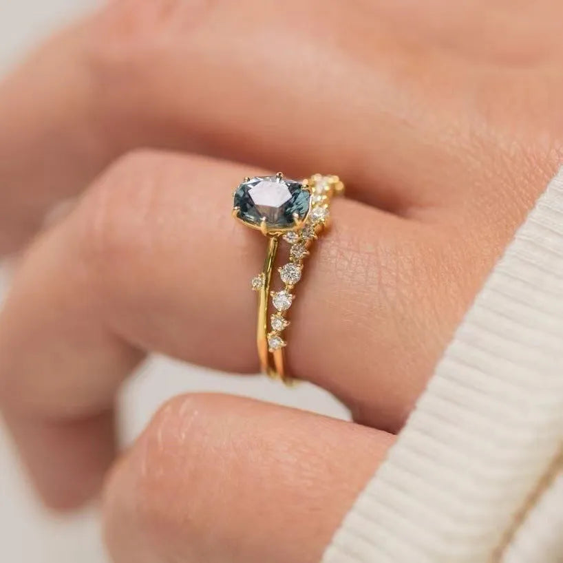 Gold-plated floral fashion ring with a central green zircon stone on a hand.
