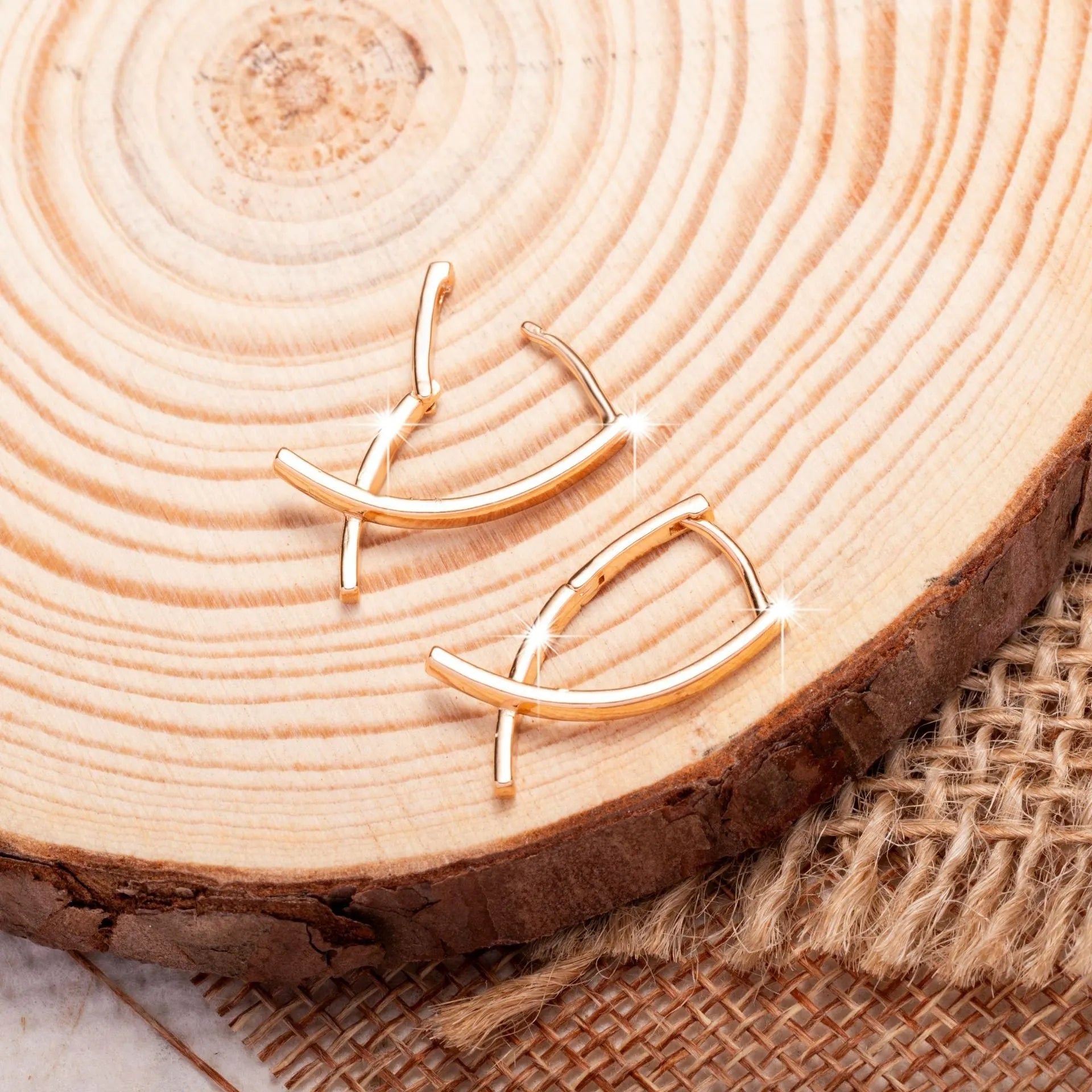Rose gold coloured cross-shaped earrings on a plain background.