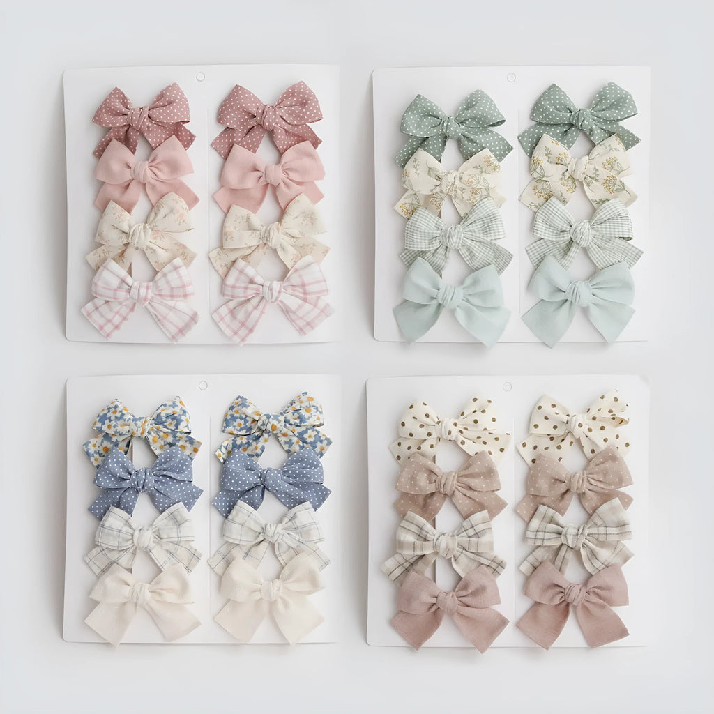 Set of eight cloth hairclips for children with dovetail bow designs in various colour patterns.