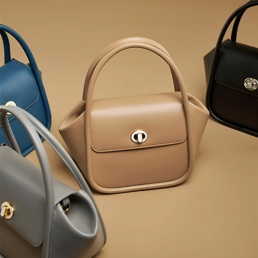 A wing-shaped cow leather tote bag with a buckle latch closure, shown in blue with a single cross-body strap.