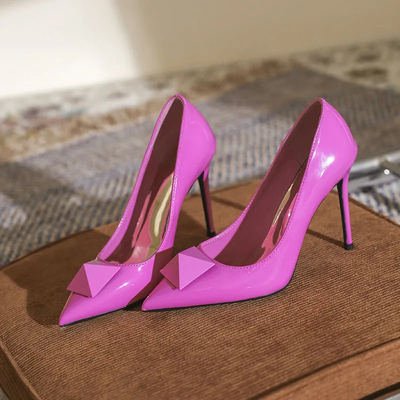 Pink patent leather women's pointed toe stiletto heels with buckle and rivet details on a low-top ankle.