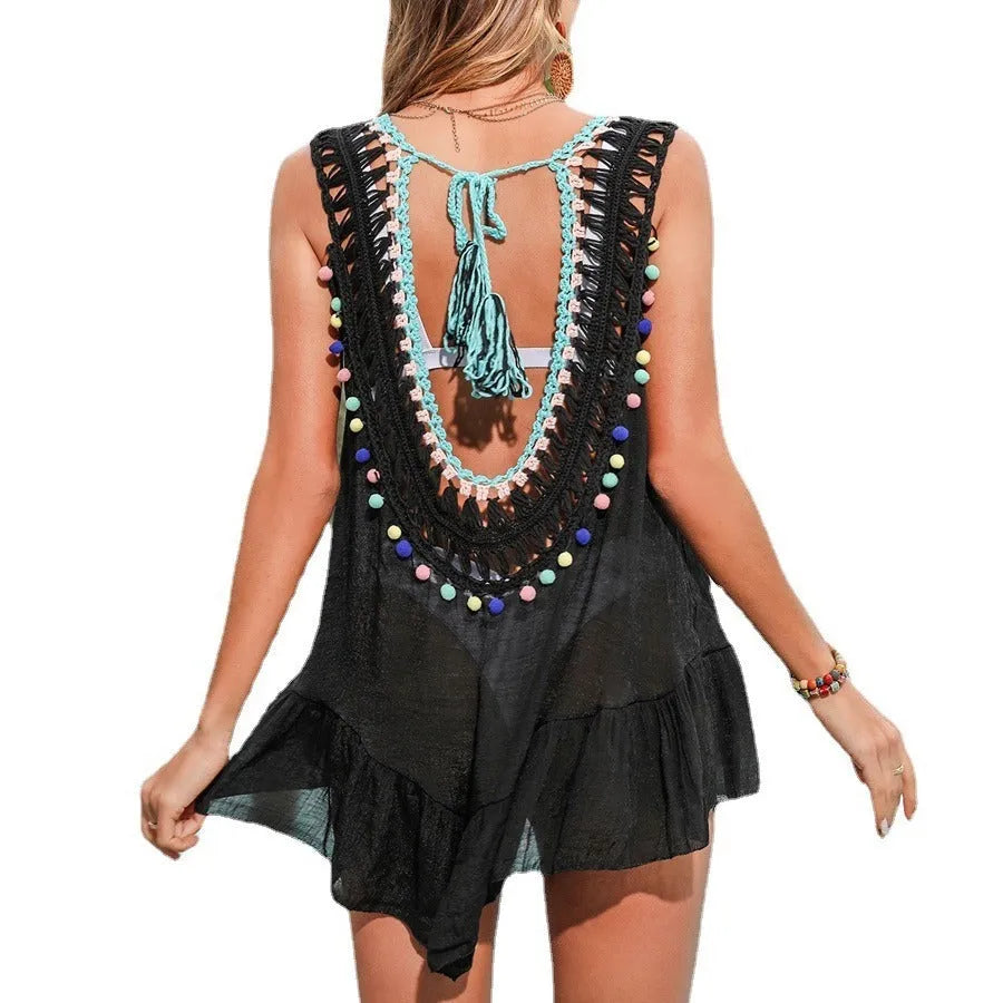 Black hand-crocheted women's beach cover-up with cut-out ruffled design on a hanger.