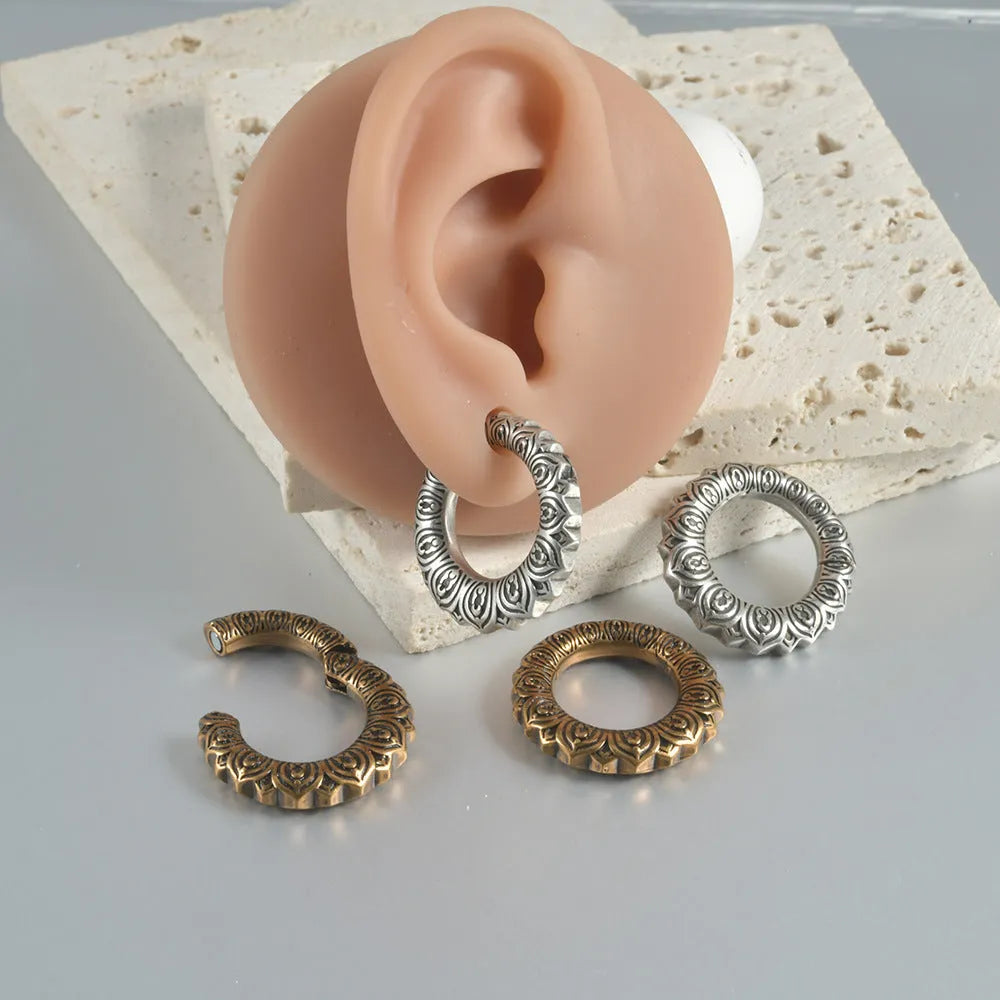 Large antique silver alloy earrings with a geometric hollow out dragon shape on a grey background.