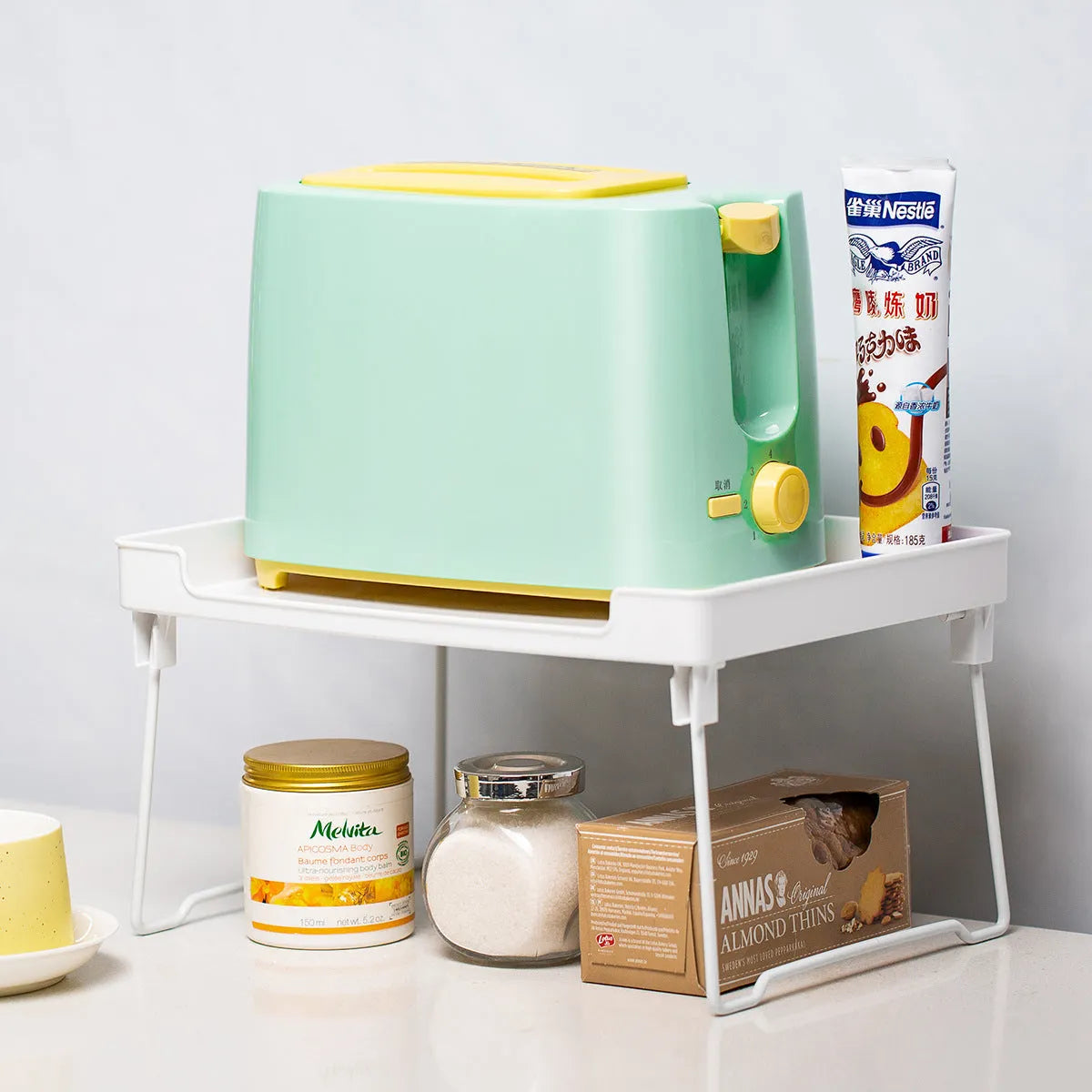 A transparent and a white plastic kitchen supplies rack for desktop or cupboard organisation.