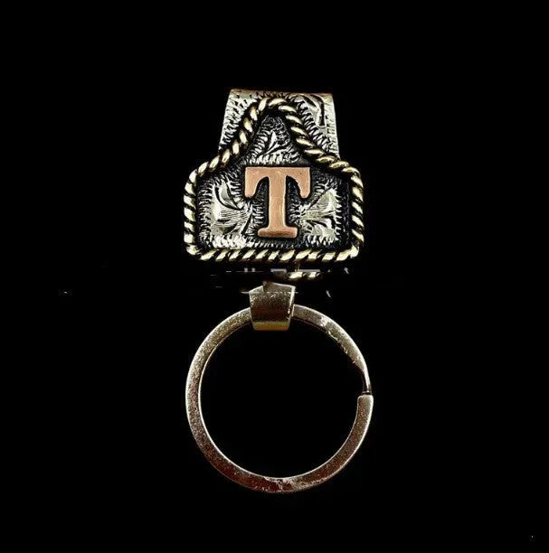 Handmade metal keychain featuring a cow tag on a belt loop design, shown in one of 26 available colours.