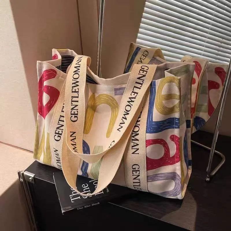 Large canvas tote shoulder bag with printed design in black letter, coloured letter, and pattern styles.