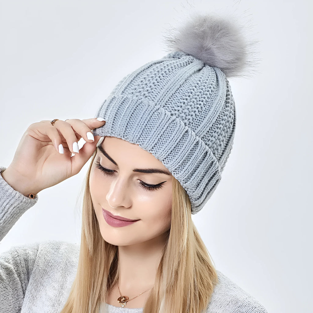 Women's black knit beanie with a faux fur pom pom and a visible satin lining inside the crown.