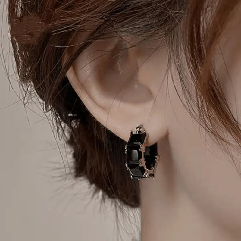 Geometric U-shaped gold tone earring with a round black zircon stone.