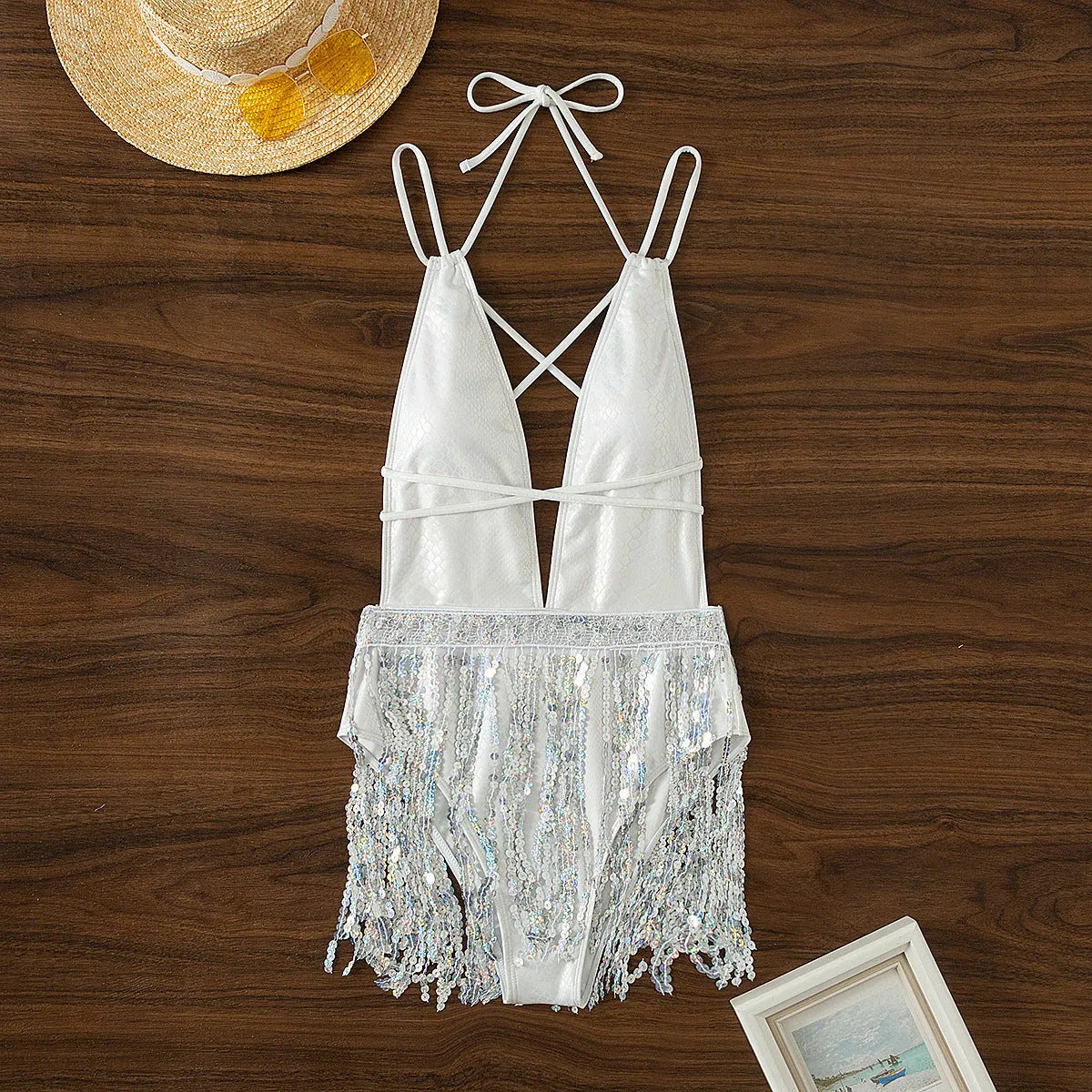 White one-piece swimsuit with a deep V-neckline and a decorative tassel.